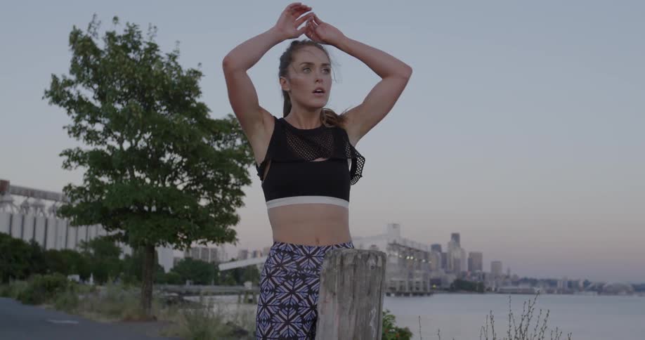 A woman stretches by the water