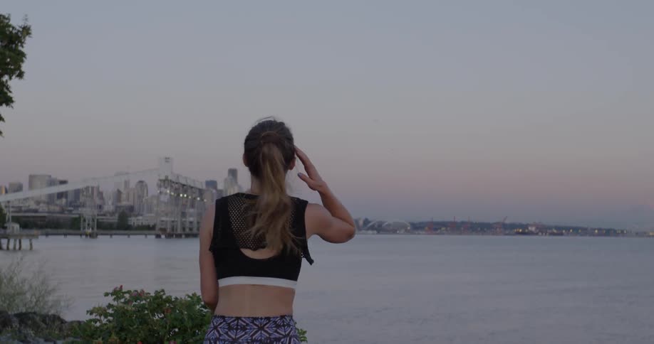Woman jogs to a stop in front of water