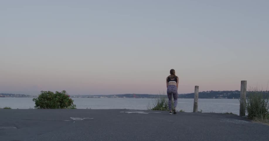 Woman jogging and then coming to a rest lakeside