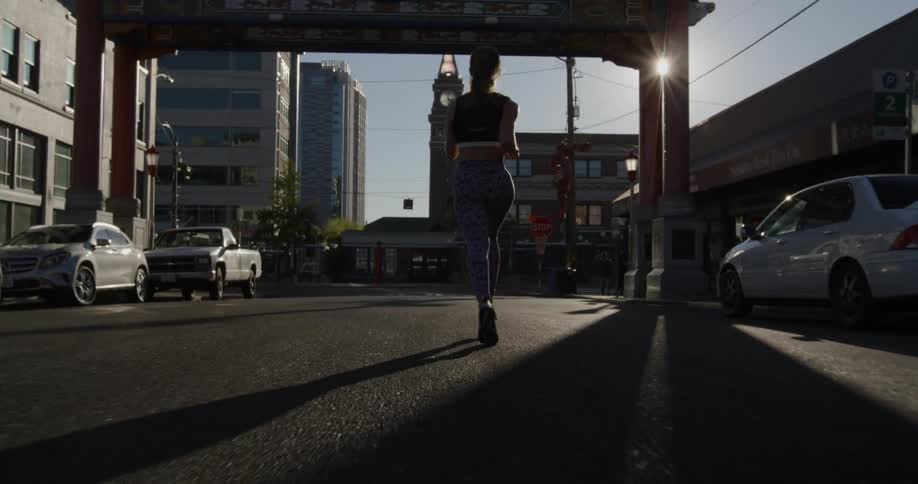 A woman jogs on a city street on a sunny day