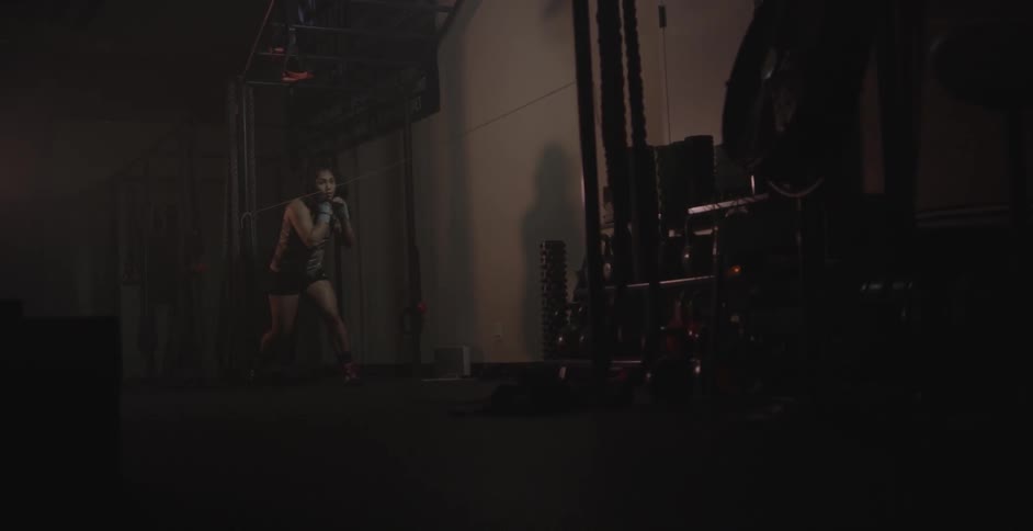 A woman is shadow boxing in a gym