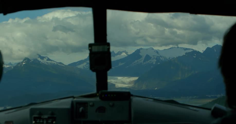 View from inside the cockpit of a plane flying towards a stunning, snow-capped mountain range