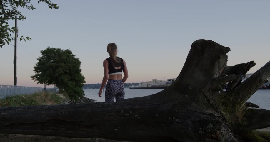 A woman in workout clothing turns away from a fallen tree she was resting on