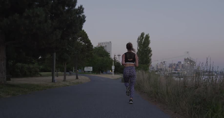 Woman jogging next to a lake in slow motion