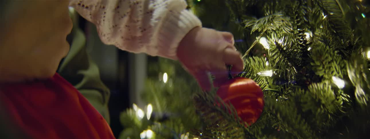 A baby is touching an ornament on a christmas tree