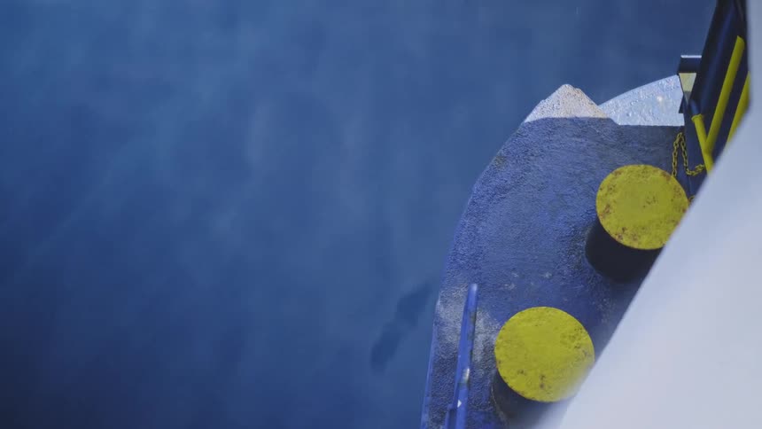Close up from a large ship sailing through the calm blue ocean during a light rain shower