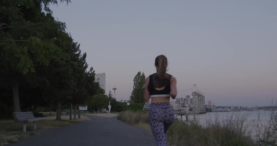 A woman jogs in a city park at dusk