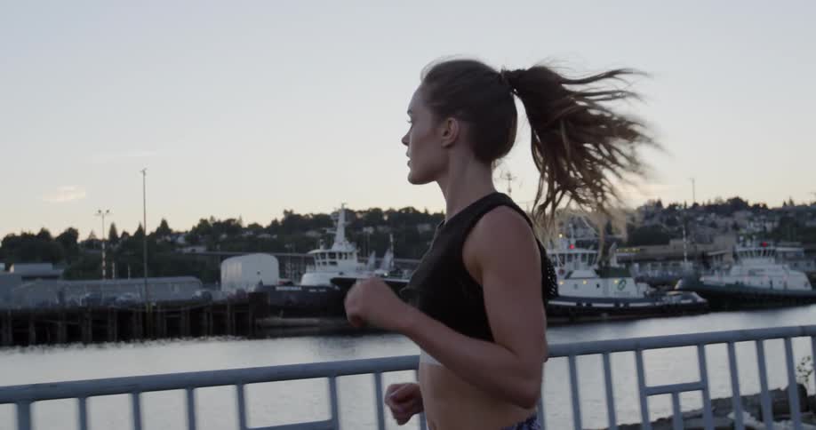 A woman is running by the water at sunset