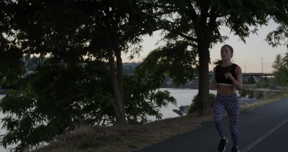 Woman jogs on a road near water
