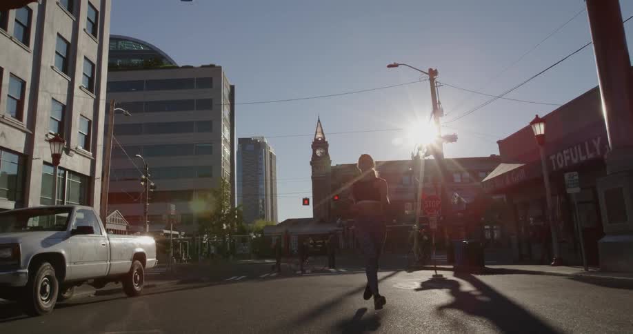Woman jogging down city street on sunny day