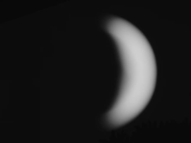 A mesmerizing black and white close-up of a crescent planet softly glowing in the dark night sky