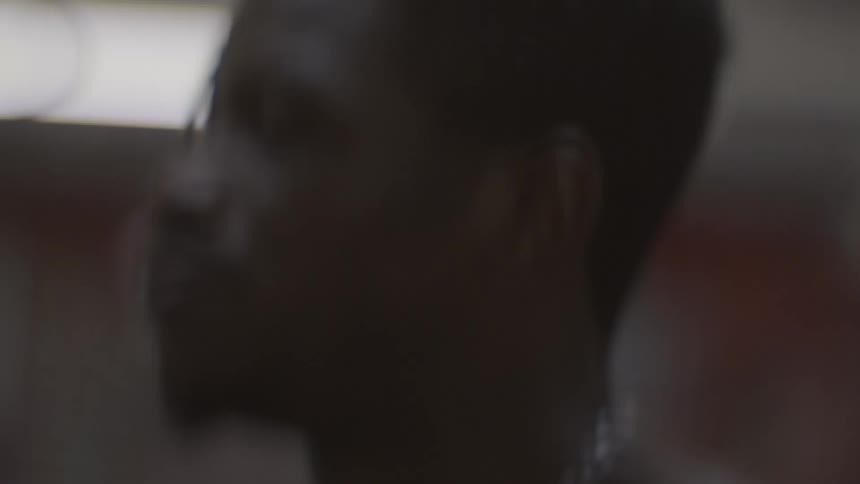 Close-up slow-motion shot of a focused shirtless man jumping up and down during a workout