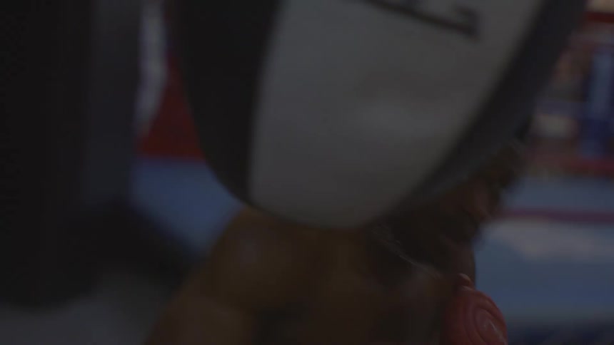 A determined boxer relentlessly punches a heavy bag during an intense training session in a dark gym