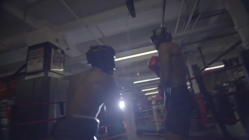 Two boxers engage in a dynamic sparring session, trading blows in the center of a gritty boxing ring