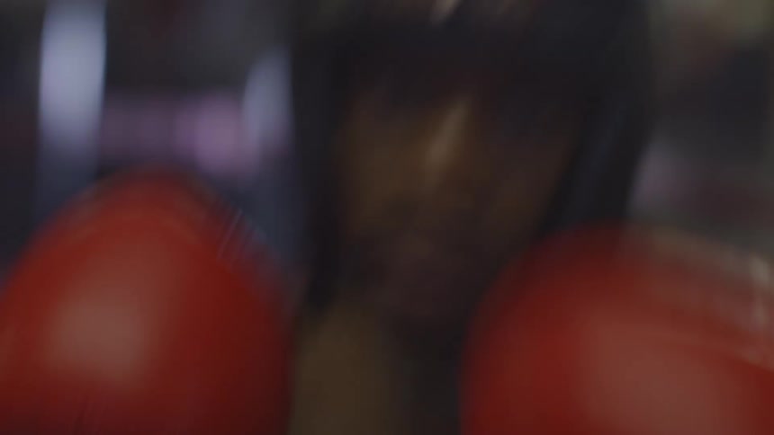 An intense and blurry first-person view of a boxer throwing punches towards the camera in a gym