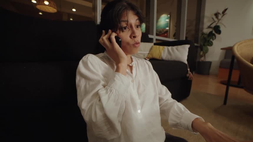 Dramatic push-in shot of a serious woman working late, talking on her phone and using a laptop on the floor
