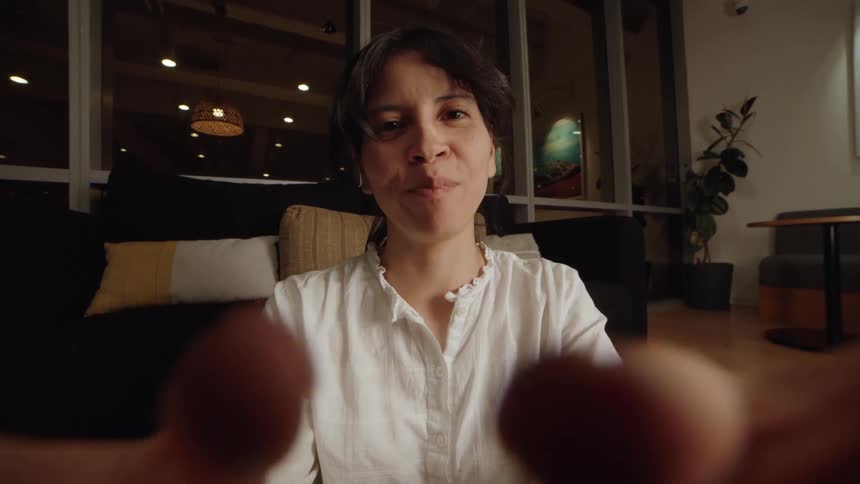 Point-of-view shot of a woman with earbuds having a cheerful and expressive video conversation at night