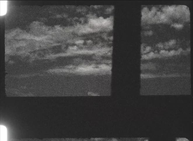 Traveling past a gritty industrial landscape with smokestacks and a large metal bridge, shot on grainy black and white film