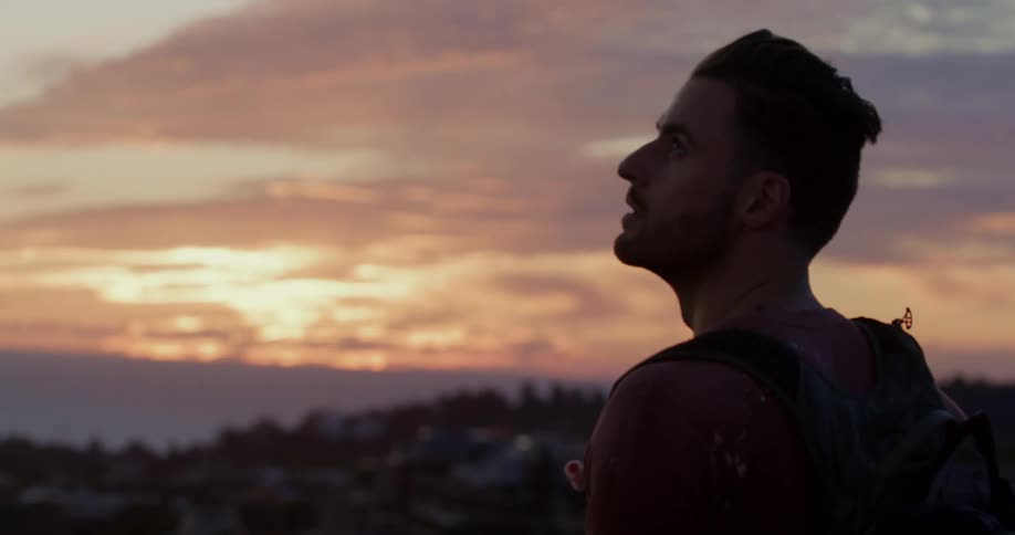 A hiker stops to take in the awe-inspiring view of a colorful sunset over the ocean
