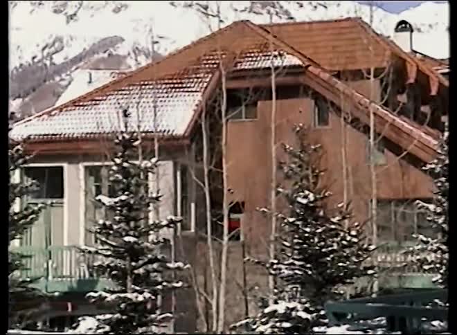 A Telluride gondola glides over a beautiful snow-covered mountain village on a bright sunny day