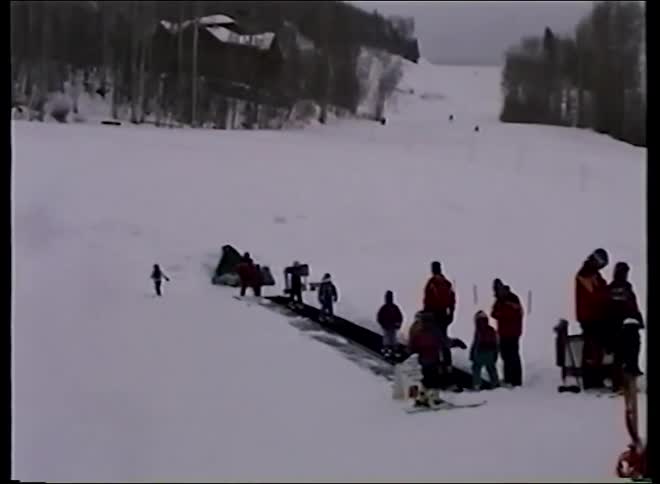 A vintage home video shows children learning to ski on a bunny slope and using a magic carpet lift