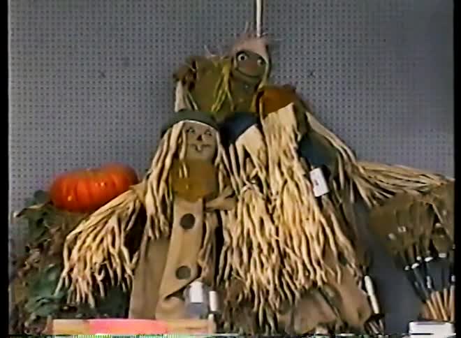 Vintage VHS footage zooms out from a display of cute scarecrows and fall decorations in a retail store