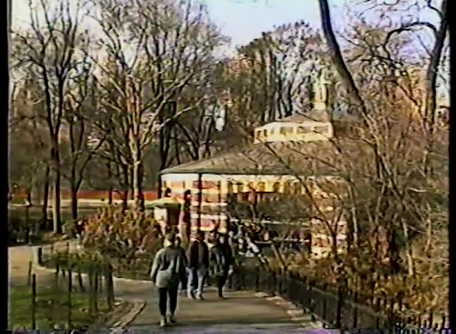 Vintage VHS footage shows people walking past the carousel in Central Park on a crisp autumn day
