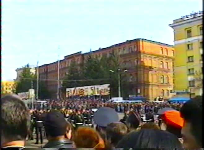 From a spectator's point of view, a large crowd gathers to watch a parade in a city square in Russia