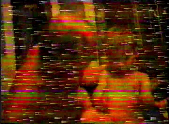 A toddler playfully touches his grandfather's face in a heartwarming, distorted VHS home movie from the 90s