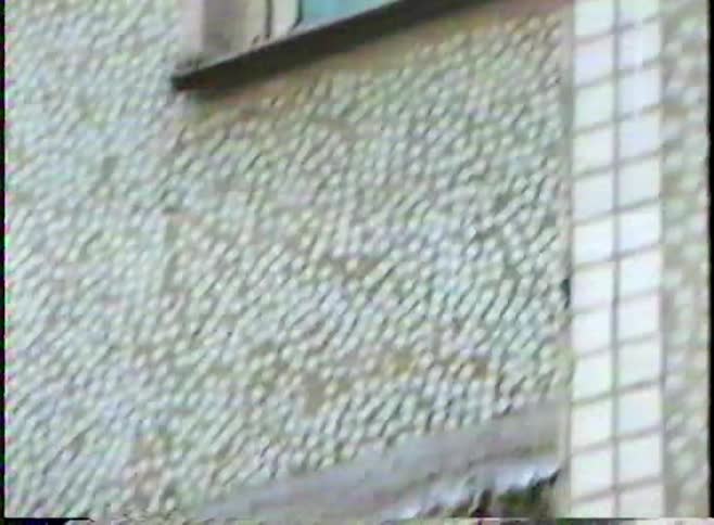 Vintage VHS footage zooms into two young boys looking down from an old apartment window