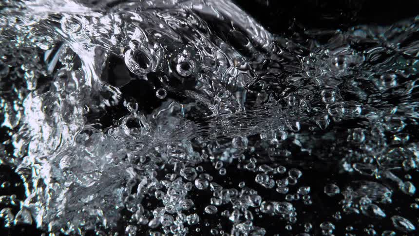 Chaotic air bubbles rise and churn in dark water in a mesmerizing slow-motion close-up