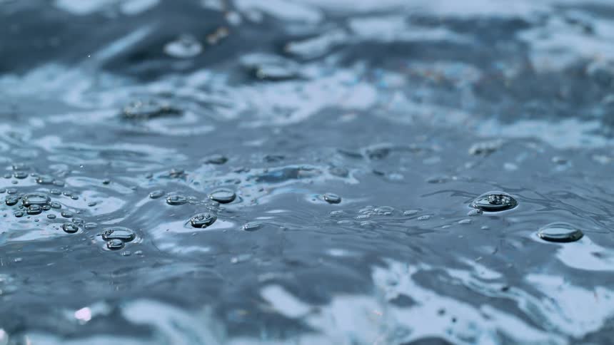 Intense macro slow motion footage shows clear water bubbling and undulating
