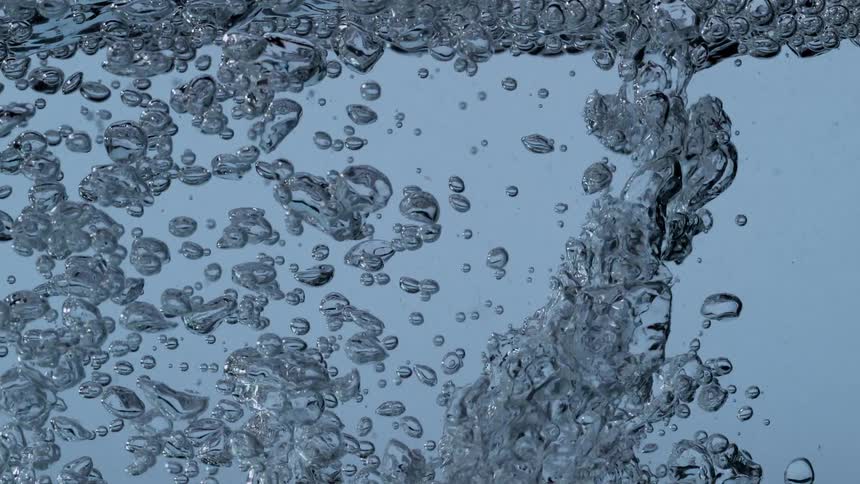 Slow motion close-up of turbulent air bubbles rising in clear blue water