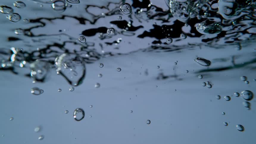 Mesmerizing slow-motion close-up of clear water swirling and creating a cascade of air bubbles