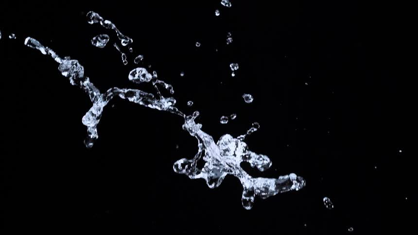 A stream of clear water splashes and breaks into individual droplets against a black background in slow motion