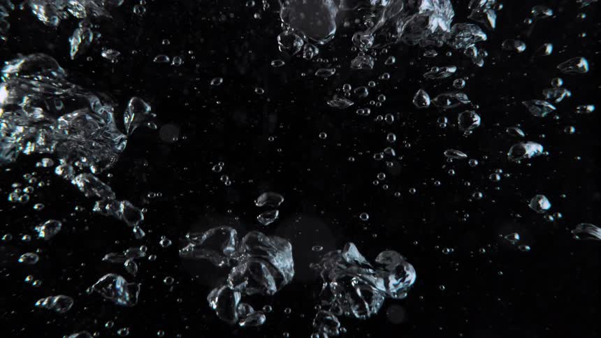 Clear water bubbles of different sizes slowly rise against a black background