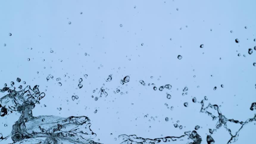 Clear water makes an elegant splash across the frame in super slow motion against a blue background