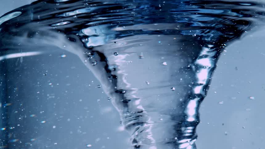 A mesmerizing close-up of a whirlpool vortex spinning in clear blue water in slow motion