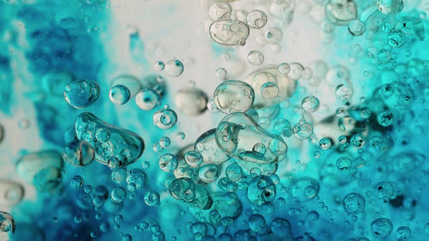 A beautiful macro shot of clear and blue tinted bubbles floating in a viscous liquid