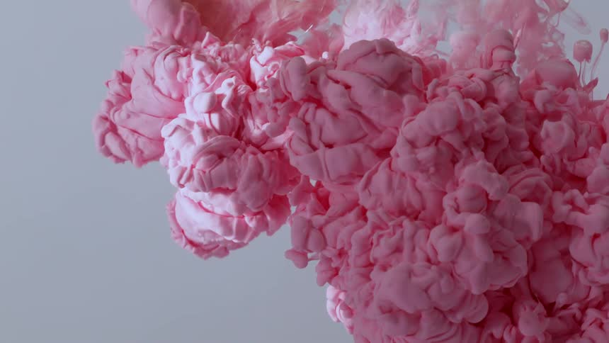 A beautiful, voluminous cloud of pink paint slowly billows and expands in water against a neutral background