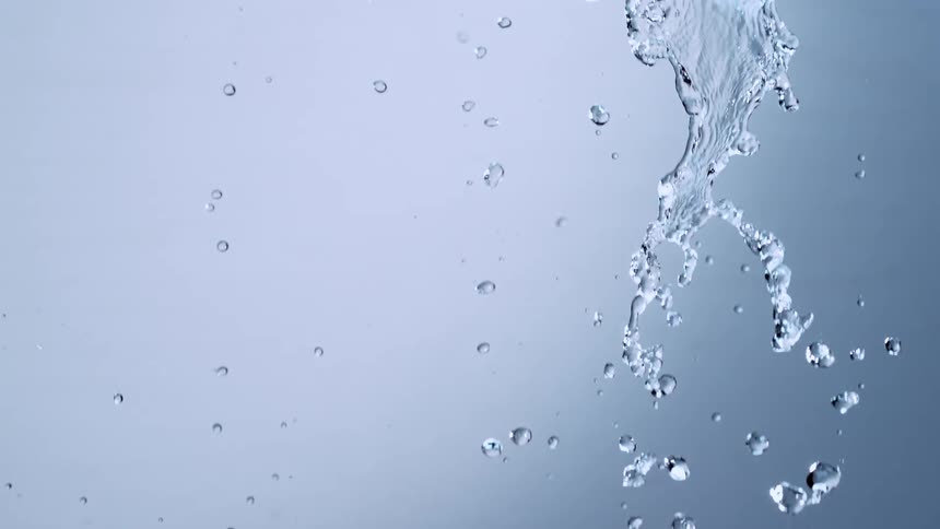 Elegant streams of water and droplets splash in super slow motion against a clean, light blue background