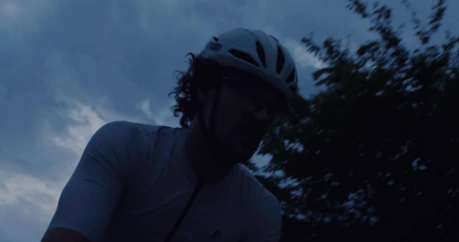 A determined cyclist powers through an intense twilight ride under a moody, cloud-filled sky