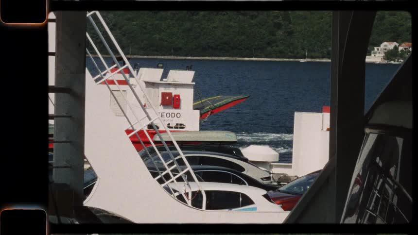 Super 8mm film captures a nostalgic view of cars and passengers aboard a ferry crossing a sunlit sea