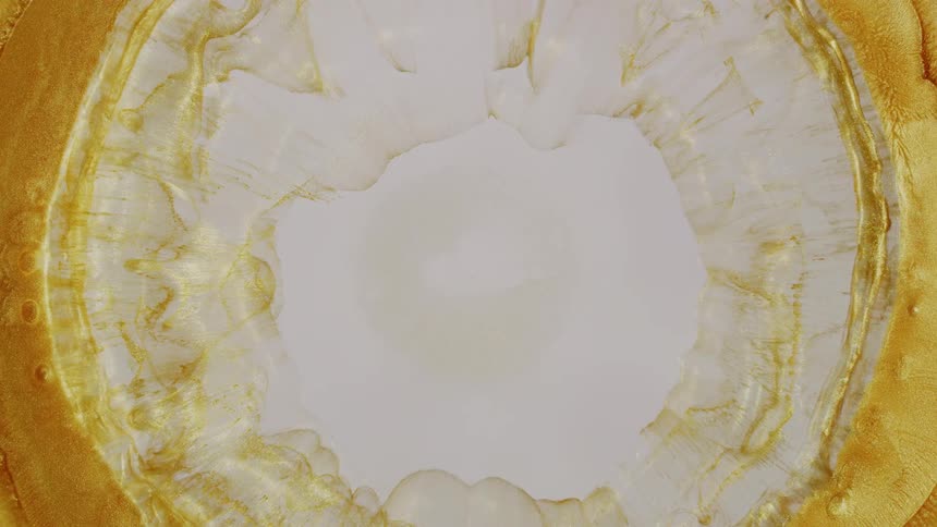 A mesmerizing top-down view of a golden liquid ring expanding and crystallizing into a transparent layer on a creamy white surface