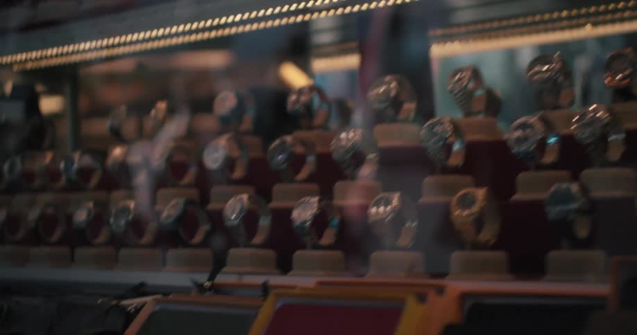 Cinematic close-up pan across a market stall displaying framed art, watches, and designer handbags