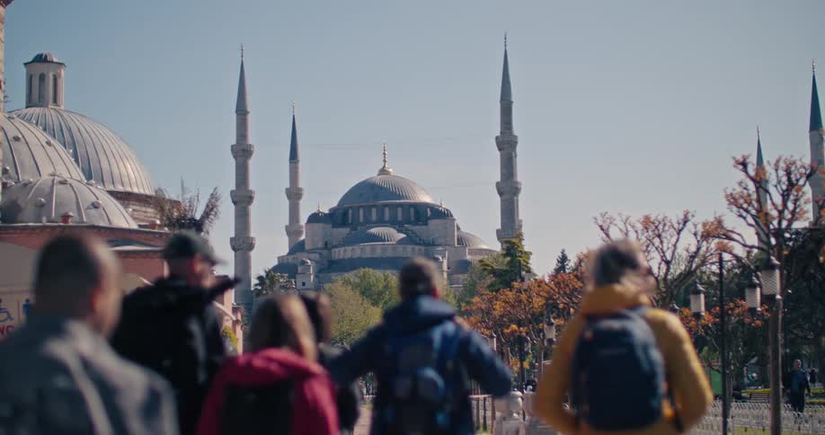 A crowd of tourists with their backs to the camera admire the Blue Mosque in Istanbul, Turkey as the shot pulls focus