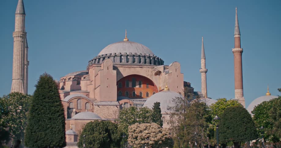 A slow zoom out reveals the grand architecture of the Hagia Sophia mosque in Istanbul, Turkey against a clear blue sky