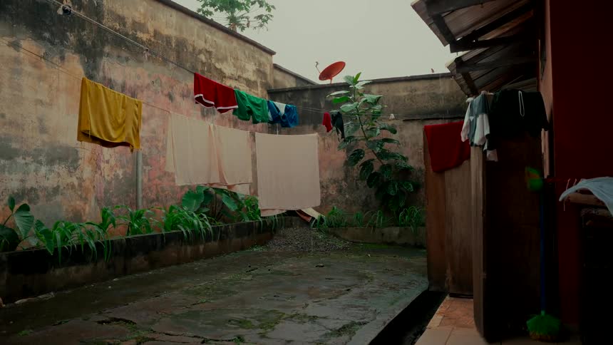 A quiet, rainy day in a weathered courtyard with laundry hanging on a line