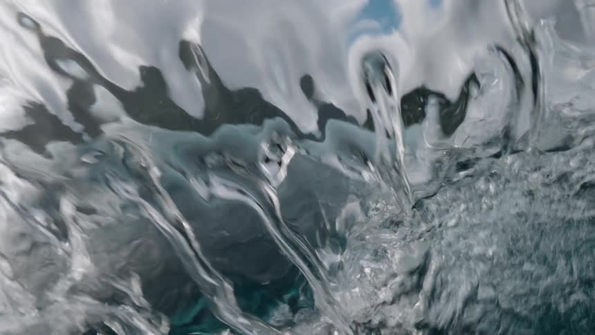 A powerful ocean wave churns and bubbles as seen from an immersive underwater perspective in slow motion
