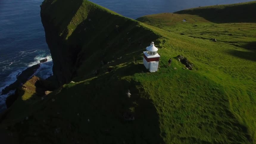 Aerial view moving along the grassy ridge next to the sea
